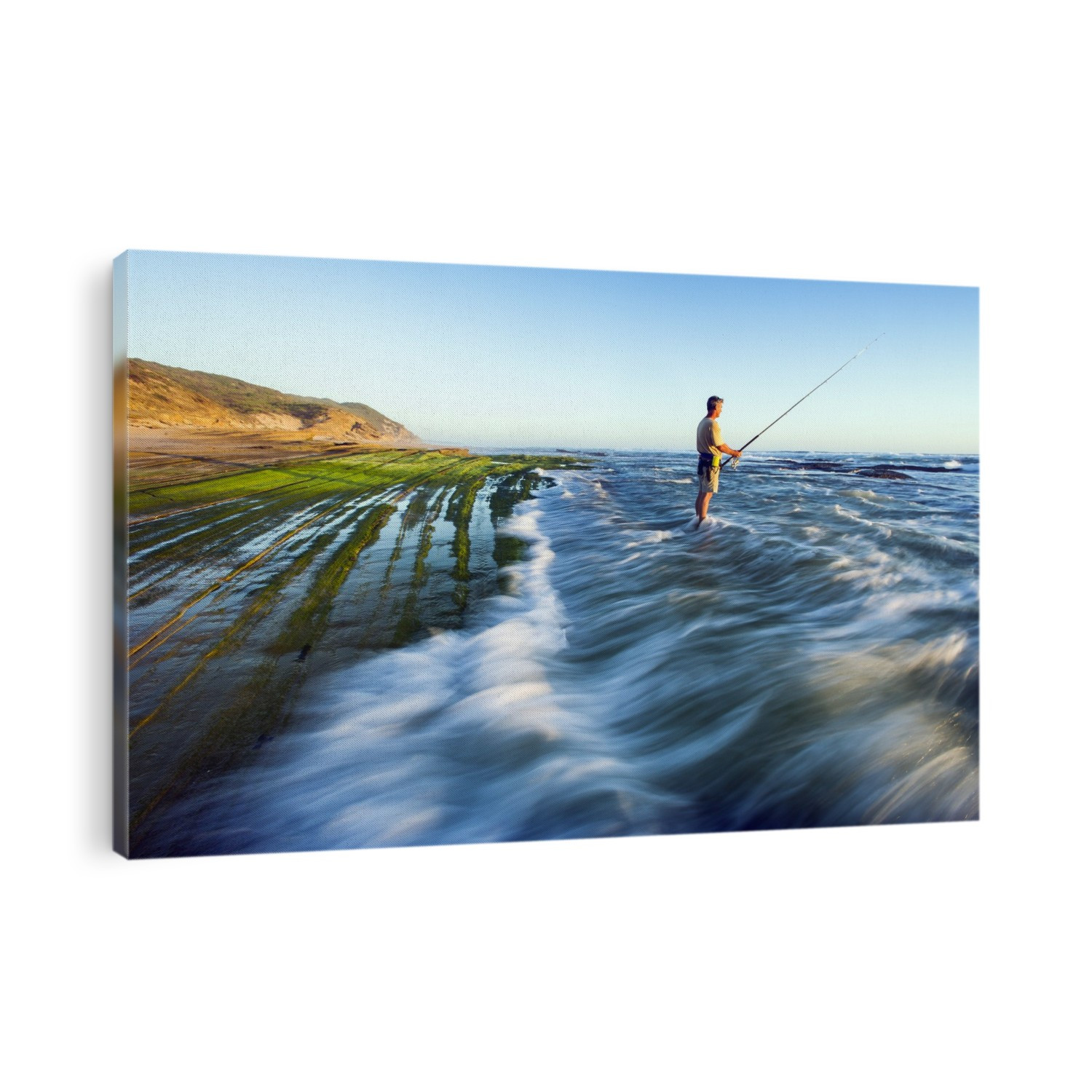 Surf fishing. Time-exposure image of a man fishing at dusk in the surf amongst algae-covered intertidal rocks. Photographed in the Goukamma Marine Protected Area, Western Cape, South Africa.