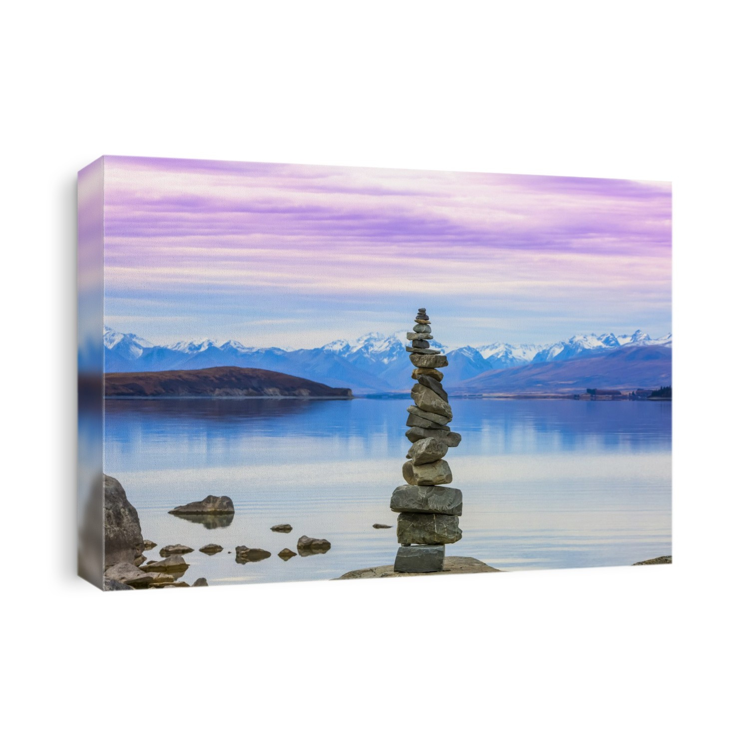 Beautiful views over the shoreline of New Zealand's Lake Tekapo at sunset. A stack of rocks sits lakeside; Lake Tekapo, Canterbury, New Zealand