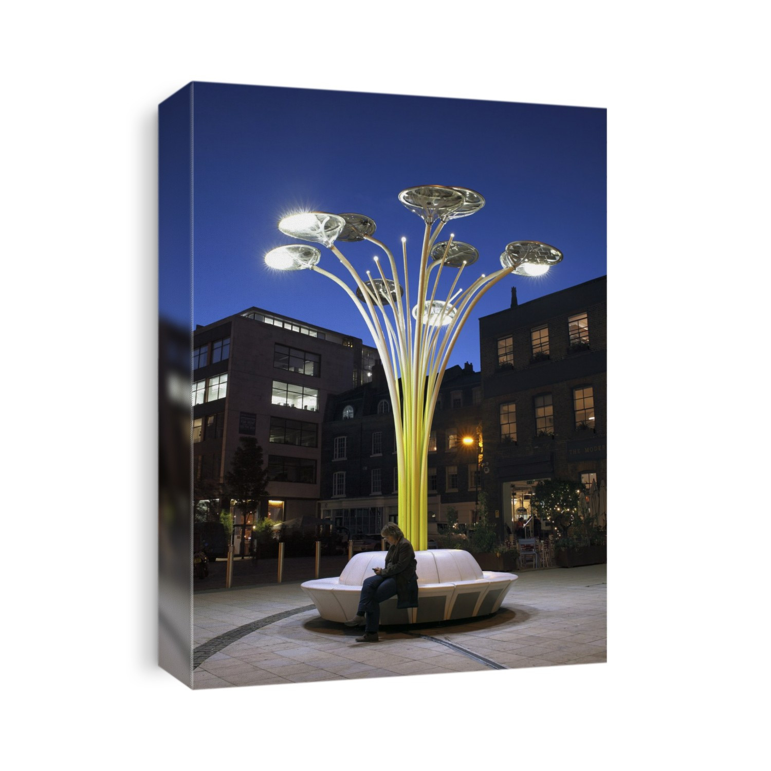 Solar street lighting. This 'solar tree' street light has photovoltaic cells on top of its circular pads. During the day they generate electricity, which is stored in batteries underneath the seats. At dusk four of the LED (light-emitting diode) lights under the pad switch on. Photographed in Clerkenwell, London, UK.
