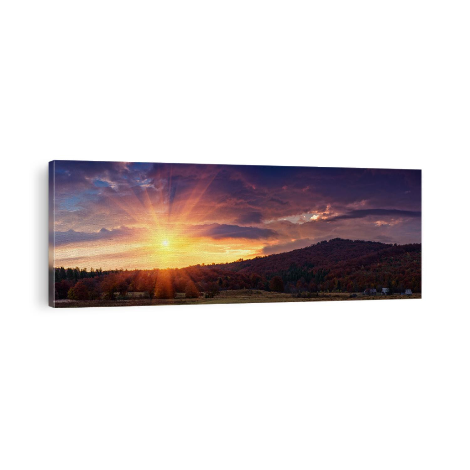 Panoramic view of the dramatic sunset in the autumn mountains. Colorful forest on the slopes. Old farm and pasture for grazing horses.