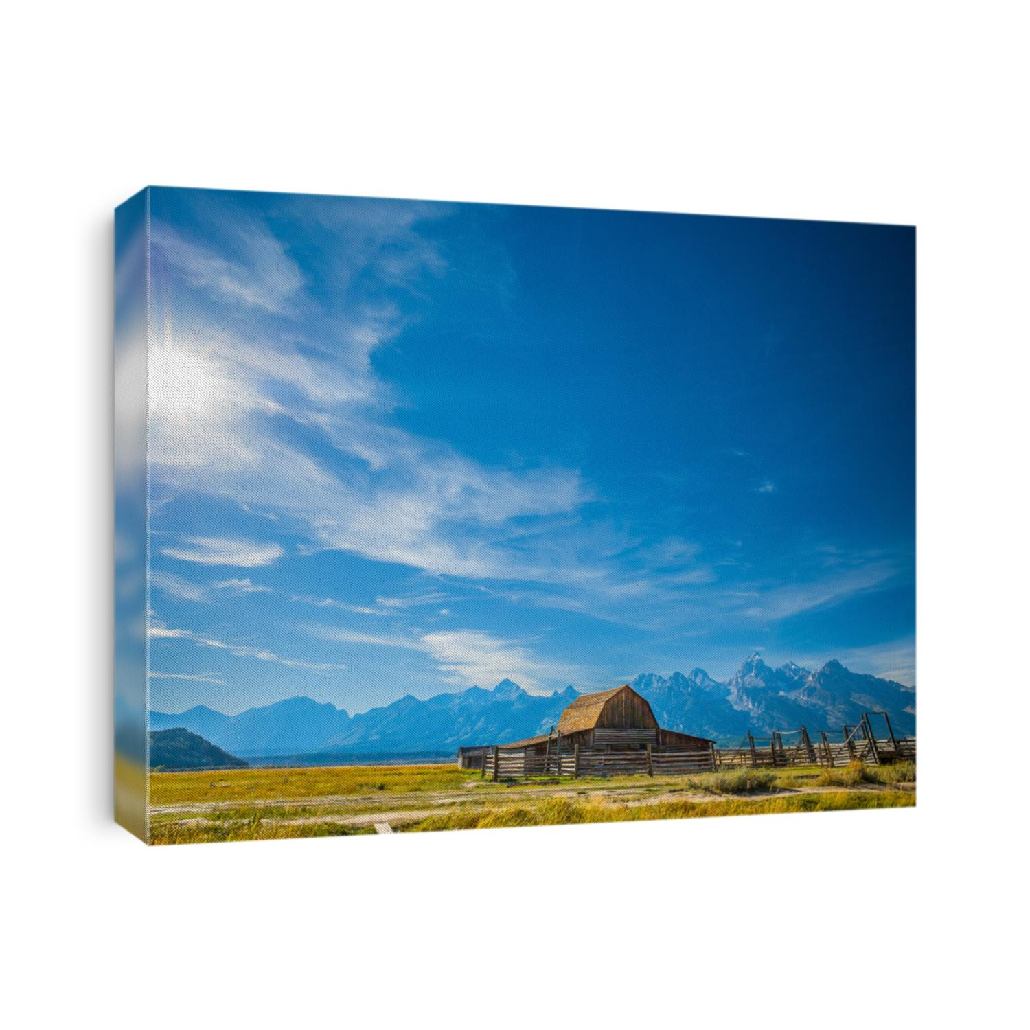 Grand Teton National Park, Jackson Hole, Wyoming.  Barn in a grass field plain against the Grand Teton mountain range with the sun shining