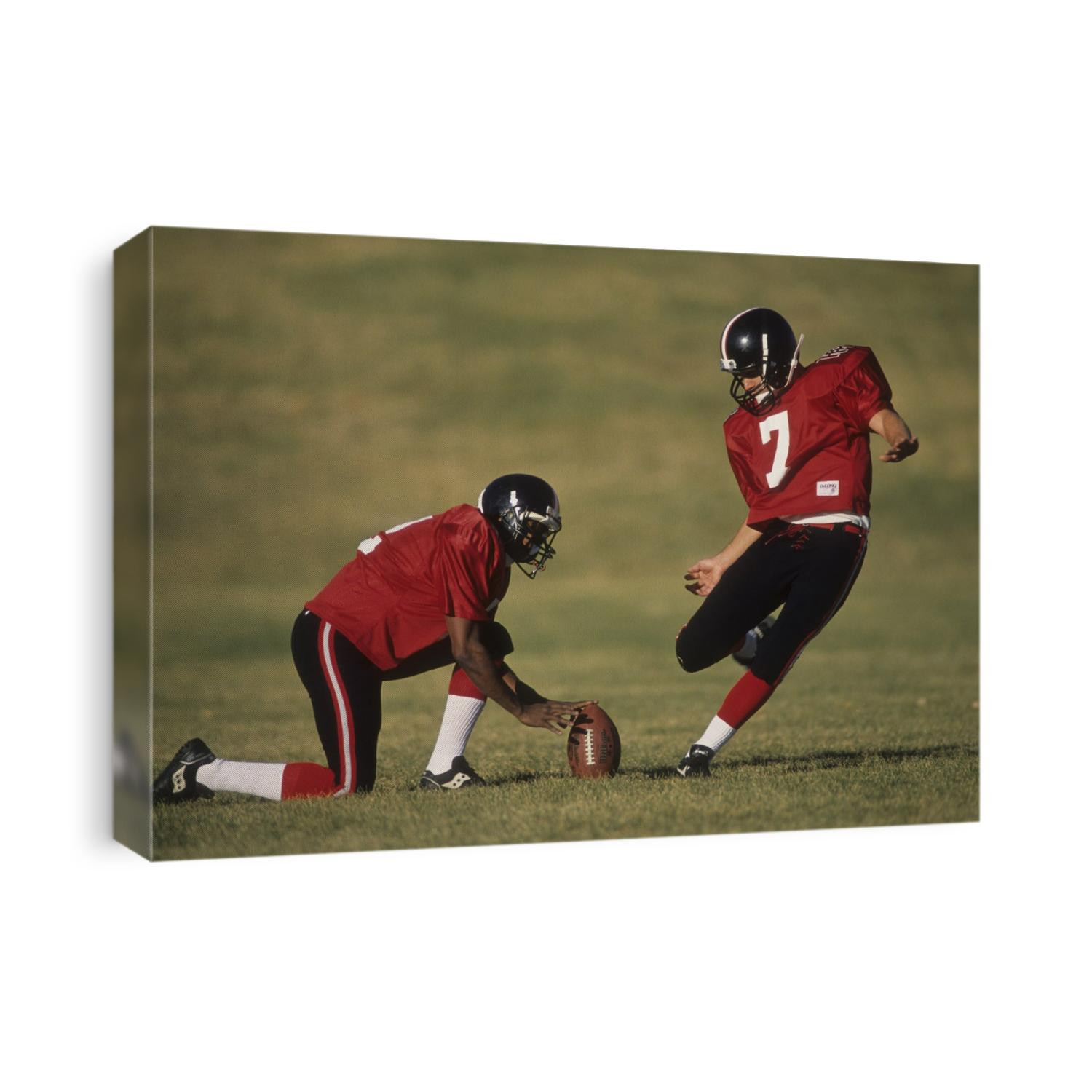 Football place kicker and holder in action.,