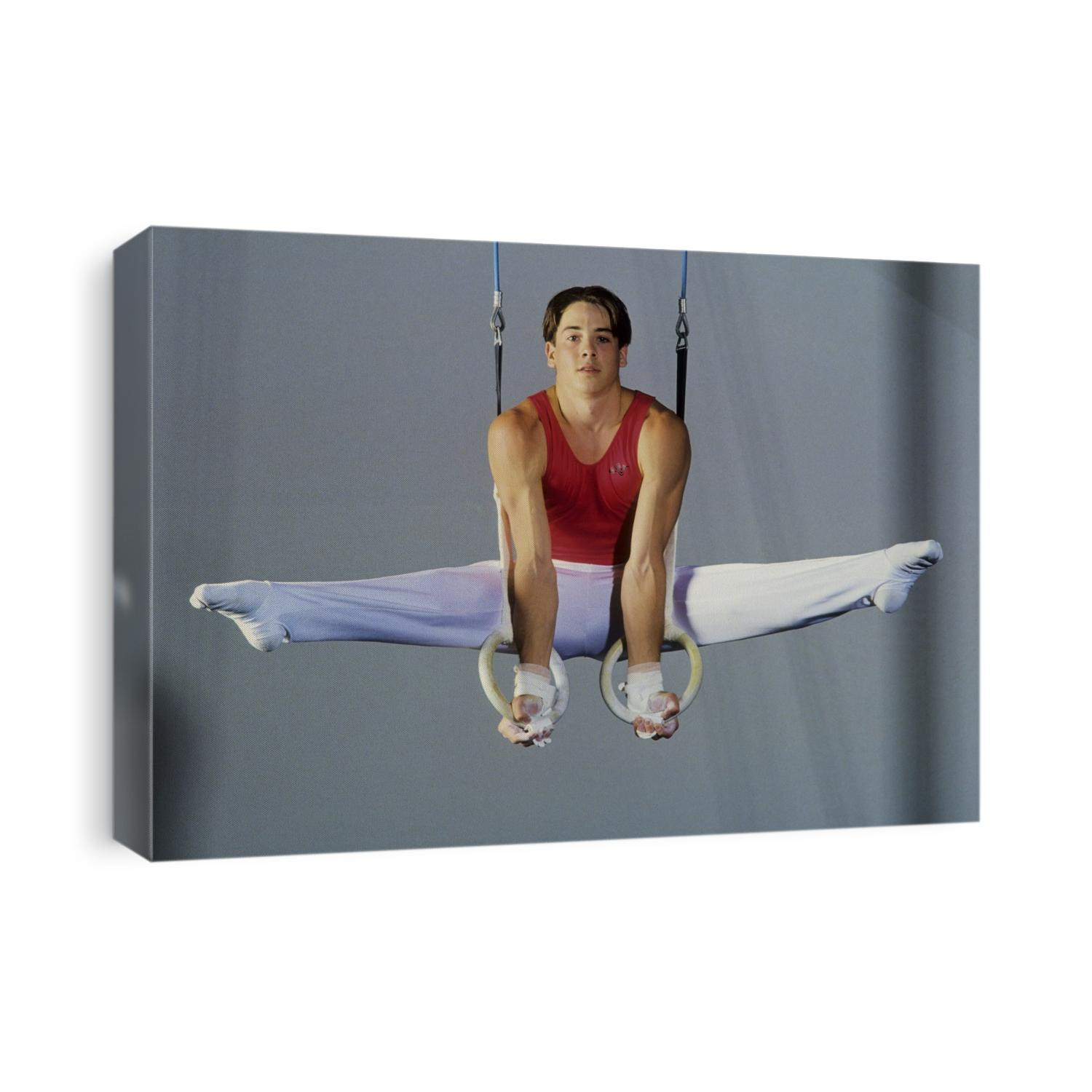Male gymnast performing on the rings.