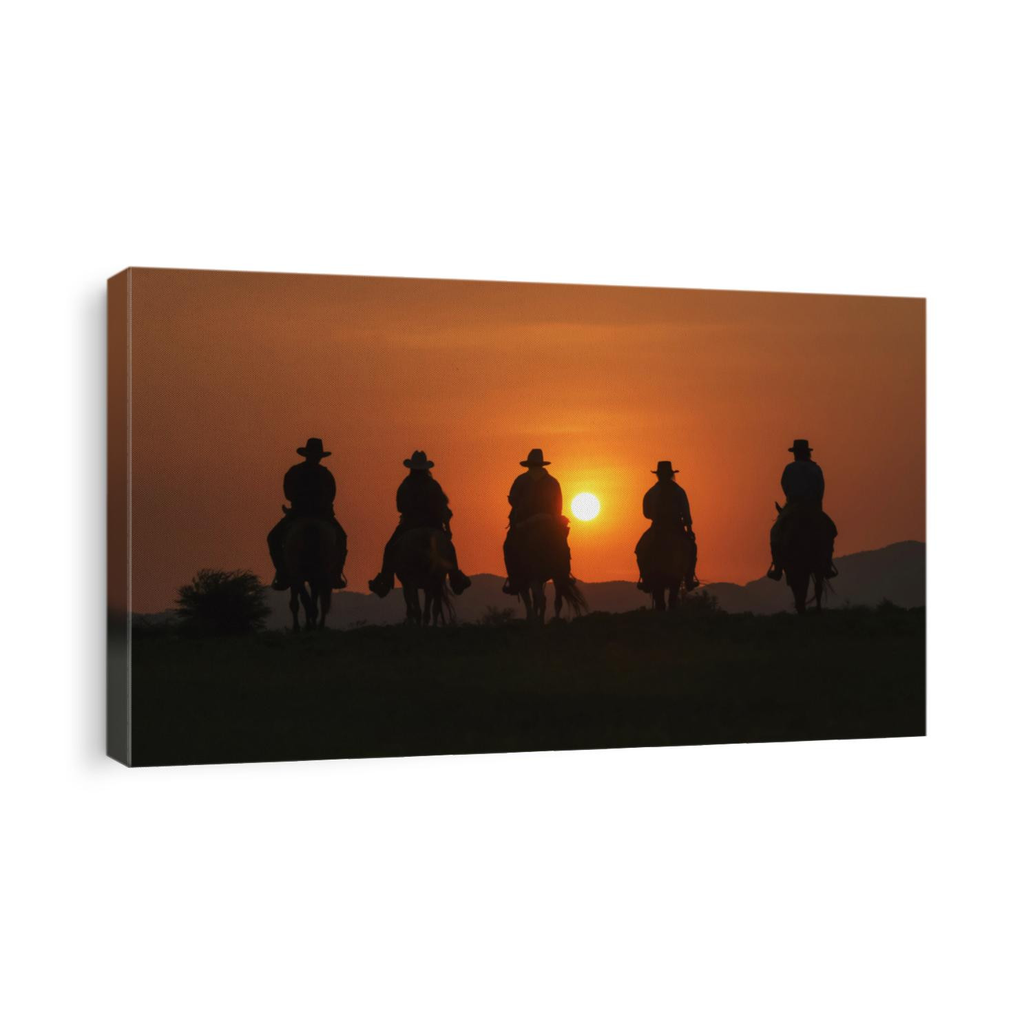 Vintage and silhouettes of a group of cowboys sitting on horseback at sunset.