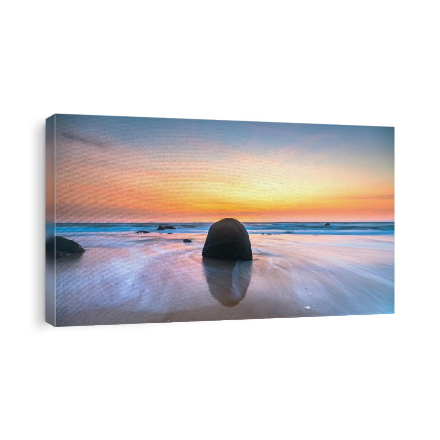 Dawn on beautiful beache with waves crashing on the shore creating silk-like streaks of different shapes piercing the rock. 