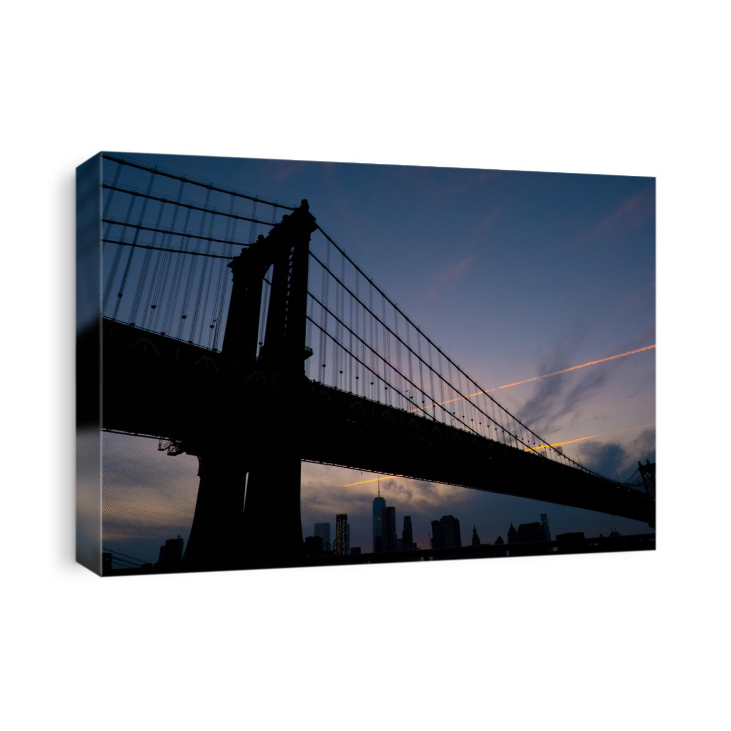 Looking up at Manhattan Bridge from Brooklyn side at sunset lower Manhattan in the background. New York City skyline as sun sets, silhouette of bridge and skyscrapers in the evening.