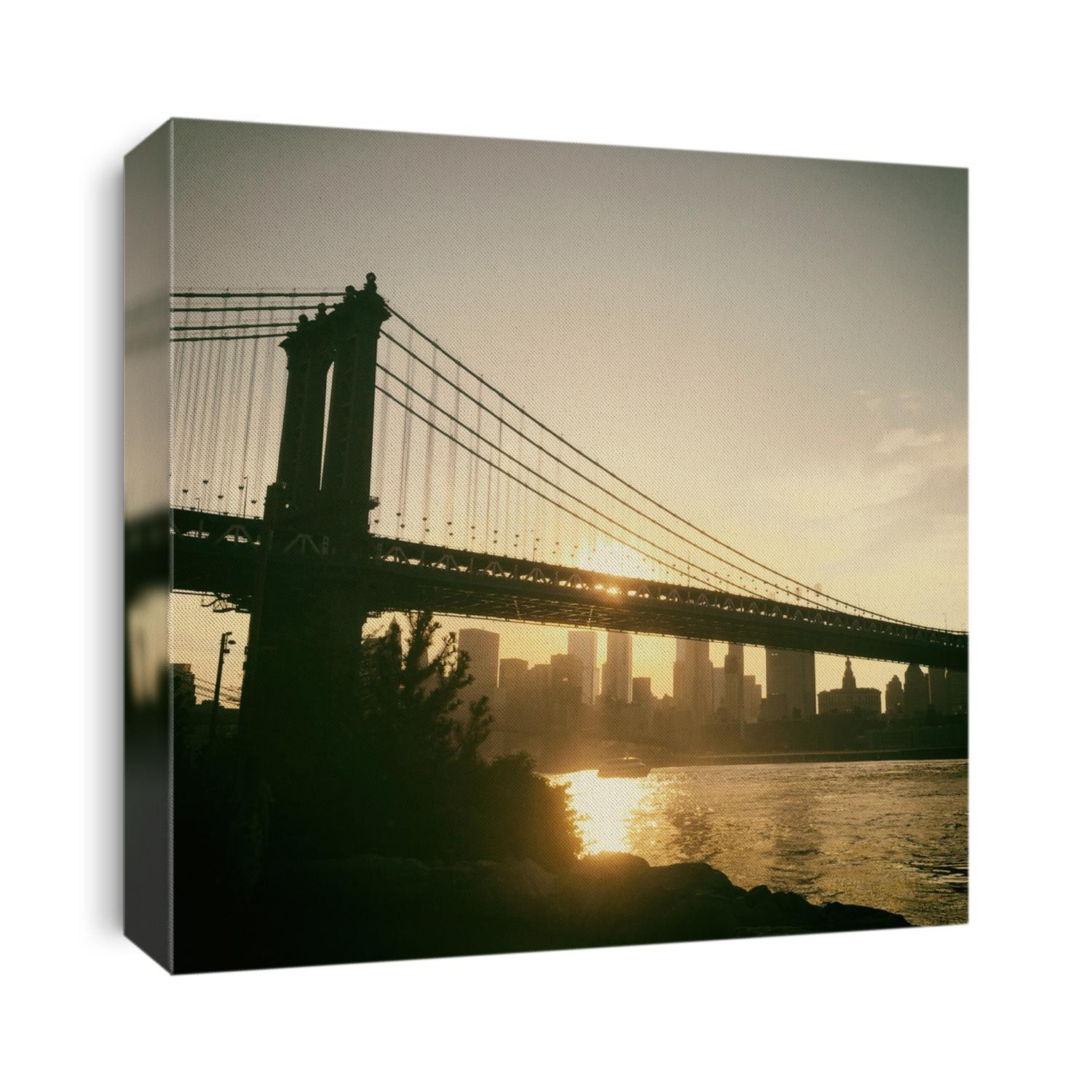 Warm light, sunset over Manhattan skyline. View of the Manhattan Bridge from Brooklyn Bridge Park looking towards Manhattan's financial district at sunset. Manhattan Bridge spanning the East River.