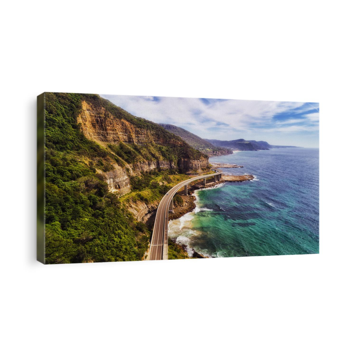 Sea cliff bridge at the edge of steep sandstone cliff on the Grand Pacific drive along pacific coast of Australia, NSW. Aerial view towards distant hill ranges on sunny summer day.