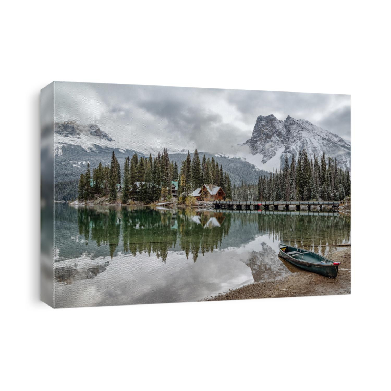 Perfect reflection of Emerald Lake lodge and a fresh blanket of snow covered majestic Canadian Rockies and a canoe nestled on the shoreline of this postcard shot.